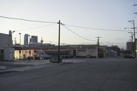 cars are parked on the street in front of an industrial town, and a sky line in