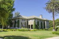 a large house sits on a lot next to the park and palm trees at one side of the mansion