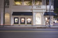 the exterior of a boutique on the side of the road at night with one person standing in front