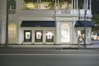 the exterior of a boutique on the side of the road at night with one person standing in front