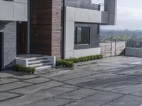 the exterior and landscape of a modern house in los angeles, california with stone and wood