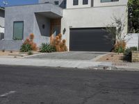 a grey house on a residential street with a garage door open and palm trees in the background