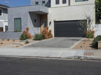 a grey house on a residential street with a garage door open and palm trees in the background