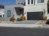 a grey house on a residential street with a garage door open and palm trees in the background