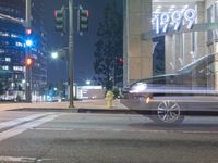 a car passing in front of a store at night time time on a city street