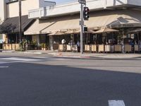 a restaurant with people sitting in chairs under an awning along a city street,