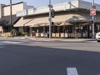 a restaurant with people sitting in chairs under an awning along a city street,