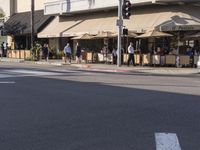 a restaurant with people sitting in chairs under an awning along a city street,