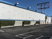 a white building with blue roof next to the street in front of it and a clock on a pole on top