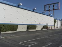 a white building with blue roof next to the street in front of it and a clock on a pole on top