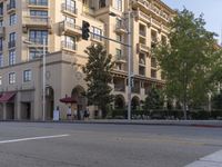 a very tall building with lots of windows next to the street intersection, and on the corner a red car is on the sidewalk