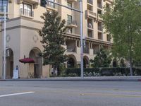 a very tall building with lots of windows next to the street intersection, and on the corner a red car is on the sidewalk