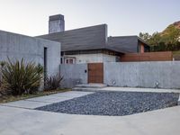 a house with a concrete foundation and a modern exterior that resembles a stone building and its driveway