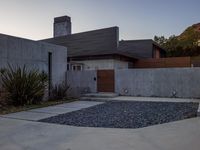 a house with a concrete foundation and a modern exterior that resembles a stone building and its driveway