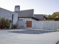 a house with a concrete foundation and a modern exterior that resembles a stone building and its driveway