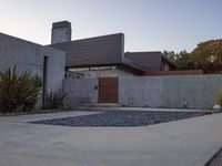 a house with a concrete foundation and a modern exterior that resembles a stone building and its driveway