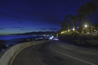 the coast with waves is at the right of this photo, a person riding his motorcycle on the street