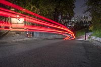 a long exposure image of a street at night with a red car streaking through it