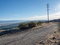 a person sitting on a bike overlooking a mountain view and hills with power lines overhead