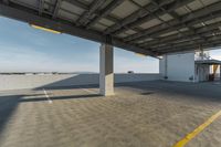 an empty parking space under an overhang in the daytime with mountains behind it on the horizon