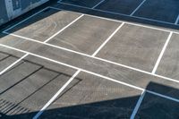 a tennis court painted with white lines on it as seen from above with shadows on the ground