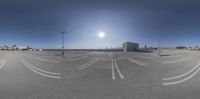 an empty parking lot with parking meters painted white and street lights shining in the background