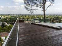 a wood deck overlooking a view of the city and trees, from above the pool