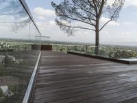 a wood deck overlooking a view of the city and trees, from above the pool