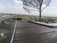 a wood deck overlooking a view of the city and trees, from above the pool