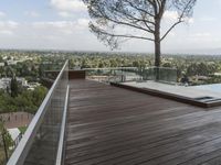 a wood deck overlooking a view of the city and trees, from above the pool