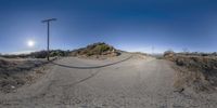 a panoramic photo of a wide open road near the beach and telephone poles