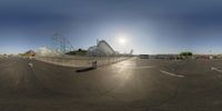 some sort of unusual photo of a huge roller coaster in an empty lot with buildings