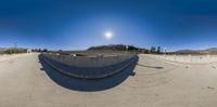 a skateboarder on the board at a skate park near a parking area while the sun shines above