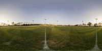 a field with three football posts and light poles in the middle and another field with no people on it