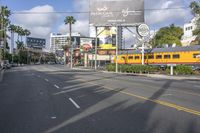 an image of a street with trains, cars and billboards in the background with palm trees