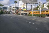 an image of a street with trains, cars and billboards in the background with palm trees