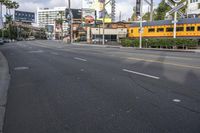 an image of a street with trains, cars and billboards in the background with palm trees