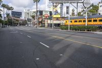 an image of a street with trains, cars and billboards in the background with palm trees