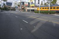 an image of a street with trains, cars and billboards in the background with palm trees