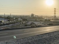 a street view, road construction in background and sun shining through the sky in the background