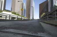 an empty road and city buildings in a big city, taken from the sidewalk of a bridge