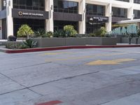 a parking lot with red concrete curb and two bushes lined up on the side of it