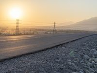 this is a picture of the sun setting over the desert and power lines on the road