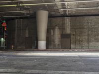 a traffic light on the street near a concrete building with no people in it that is empty and dark