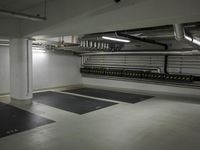 an empty underground garage with metal pipes on the walls and flooring in it, which is a set up of metal pippes