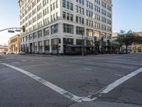 an empty street next to a tall white building with windows on the second floor and a sign indicating the end