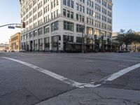 an empty street next to a tall white building with windows on the second floor and a sign indicating the end