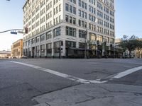 an empty street next to a tall white building with windows on the second floor and a sign indicating the end