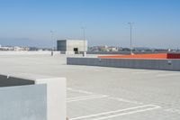 a skateboarder is on the top of the concrete ramp in the parking lot