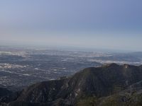 an aerial view of the city and surrounding hills with a person standing in a dark suit